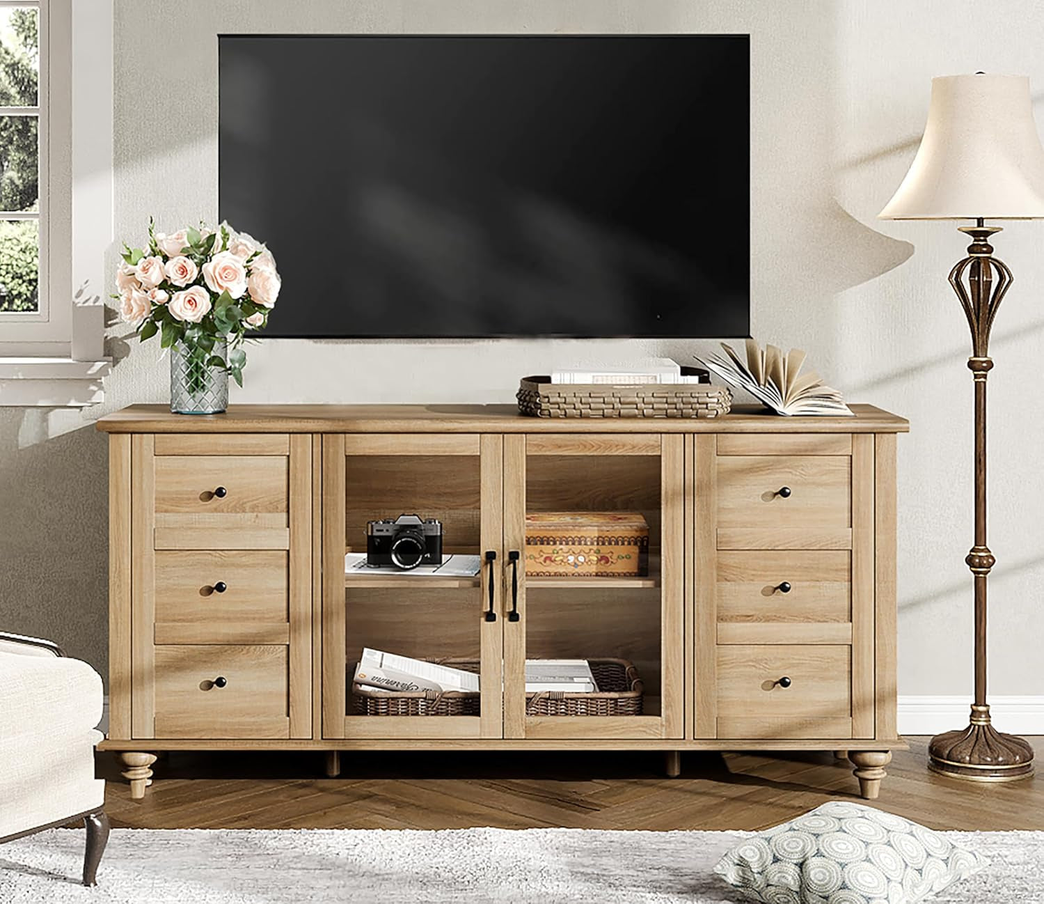 Wooden entertainment console with TV above, decor items on shelves, and a lamp to the right.