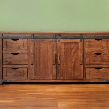 Wooden dresser with multiple drawers and doors against a green wall.