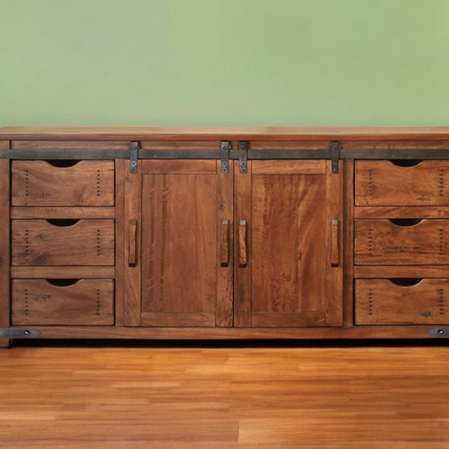 Wooden dresser with multiple drawers and doors against a green wall.