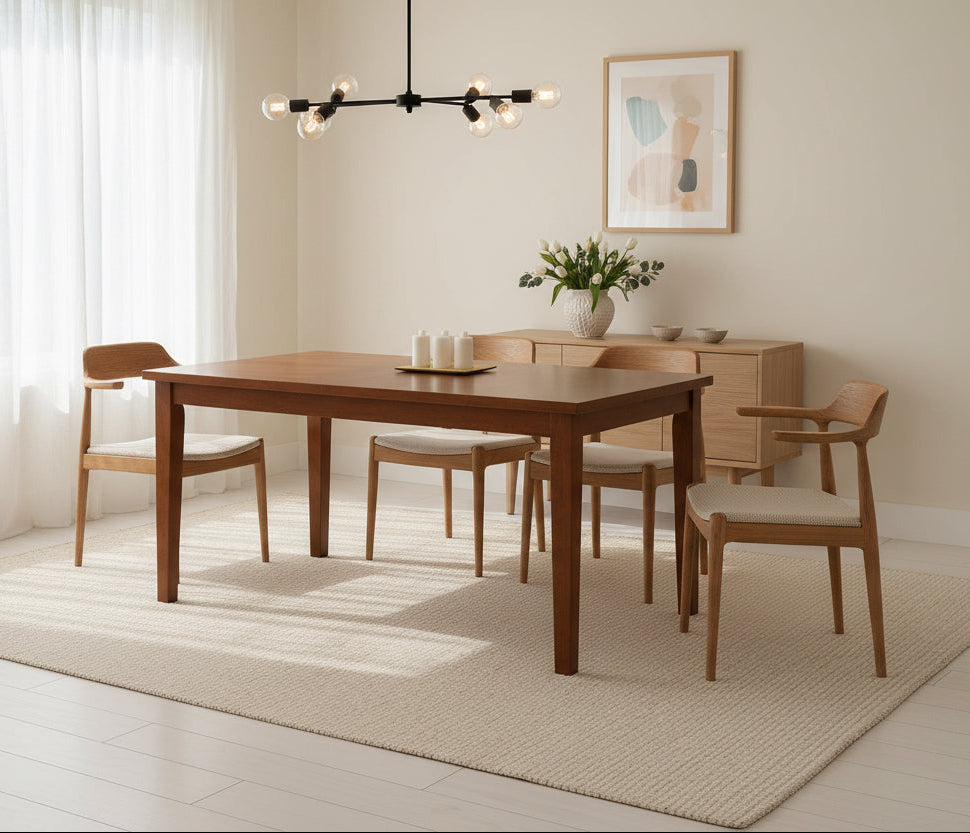 Wooden dining table with a tray of white candles in a room with warm lighting.