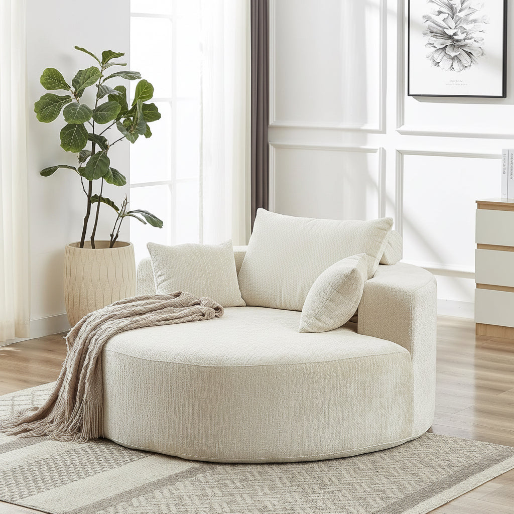 Woman reading a book on a large beige ottoman in a bright living room.