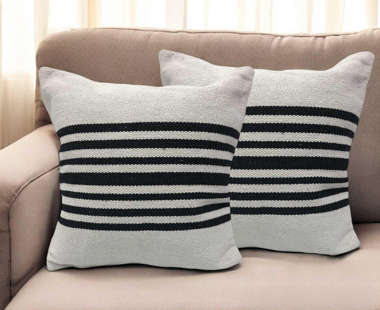 Two striped pillows on a beige couch with a neutral background