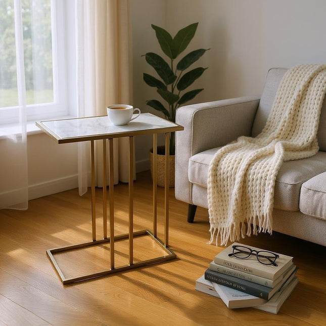 Living room with a small table, books, and a cup near a sofa with a blanket.