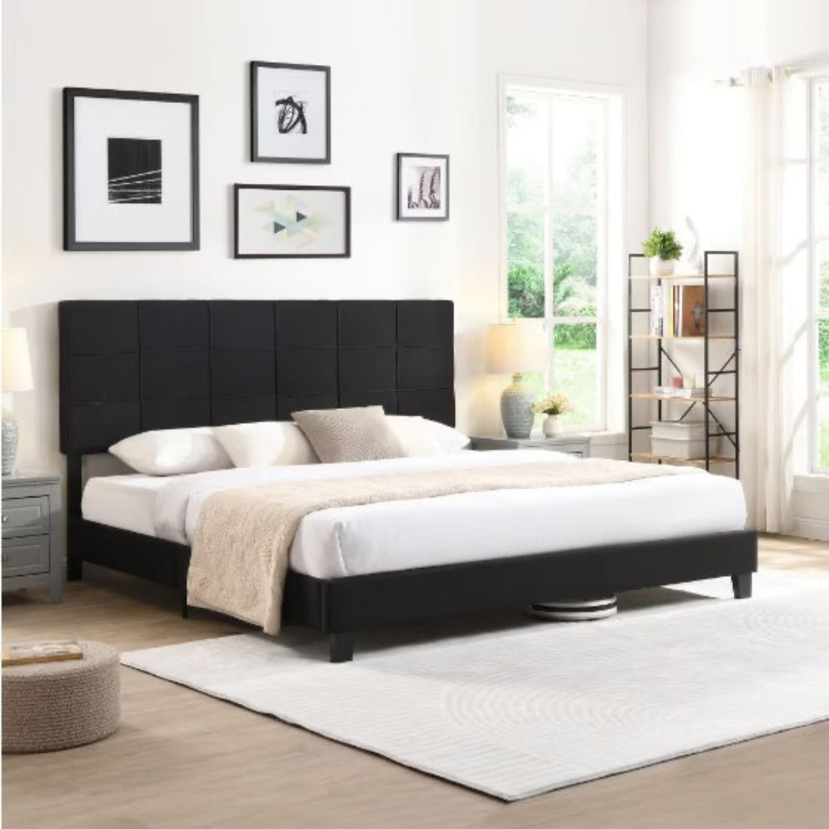 Black upholstered bed in a bright bedroom with white walls and large windows.