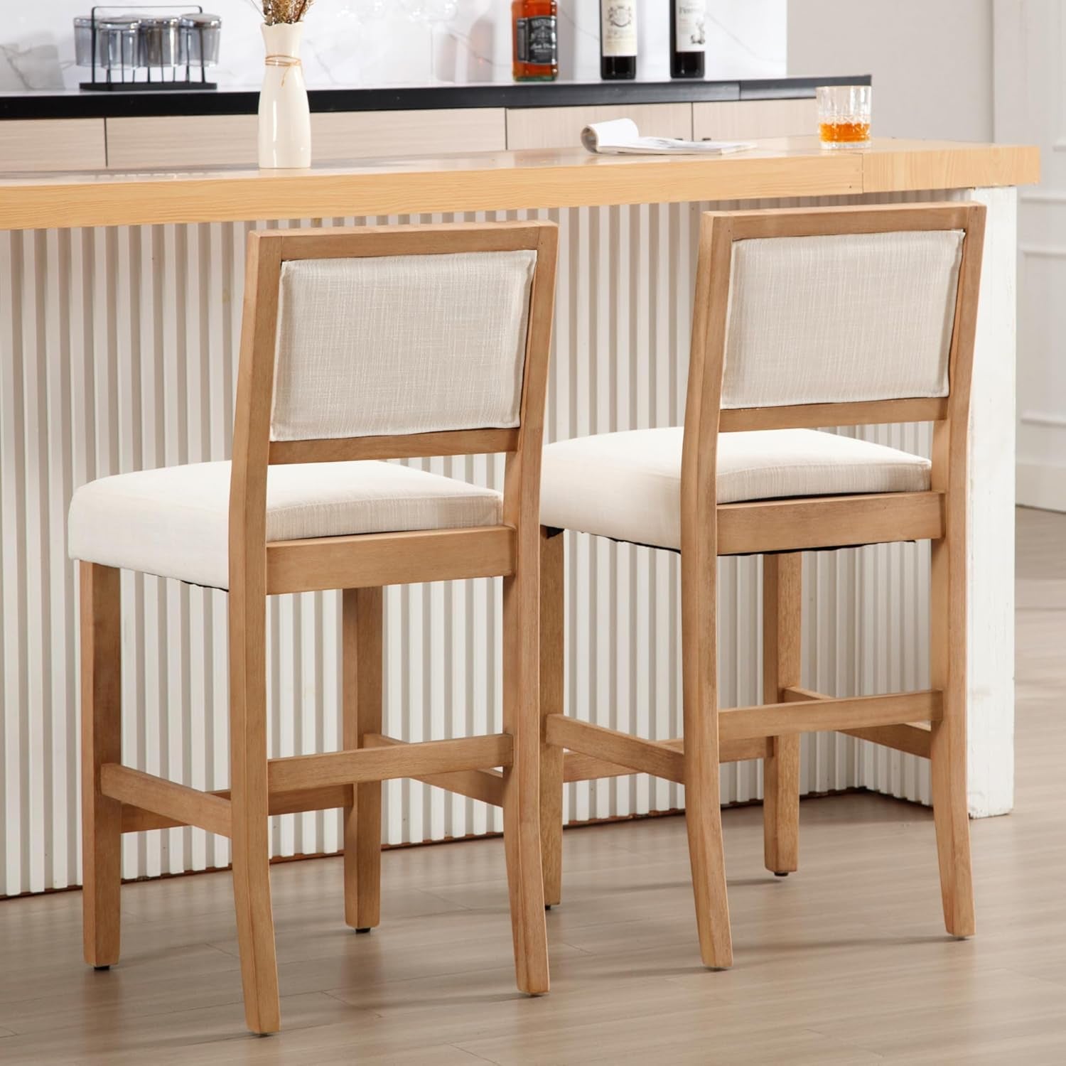 Two wooden bar stools with white cushioned seats in a kitchen setting.