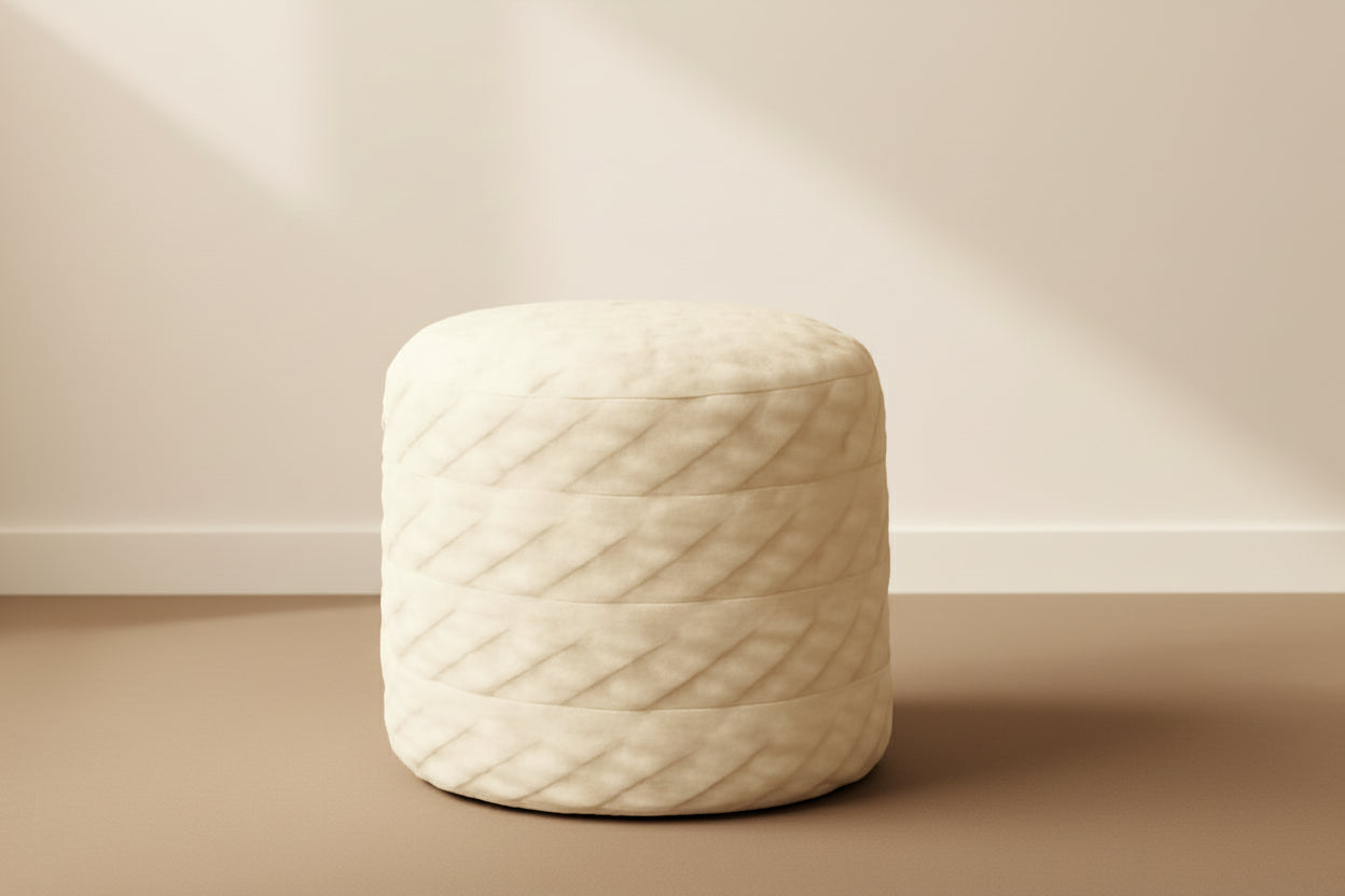 White textured ottoman in a room with a wooden side table and decorative items.