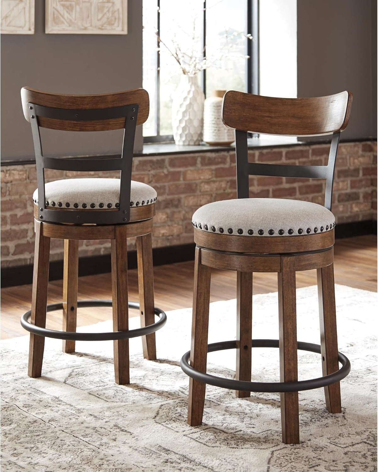 Two wooden bar stools with cushioned seats in a room with a brick wall and window.