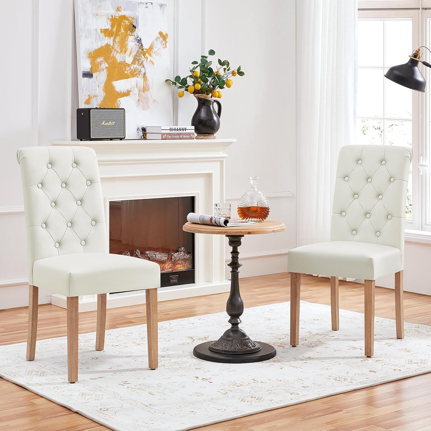 Two white tufted chairs in a living room with a fireplace and decorative items.