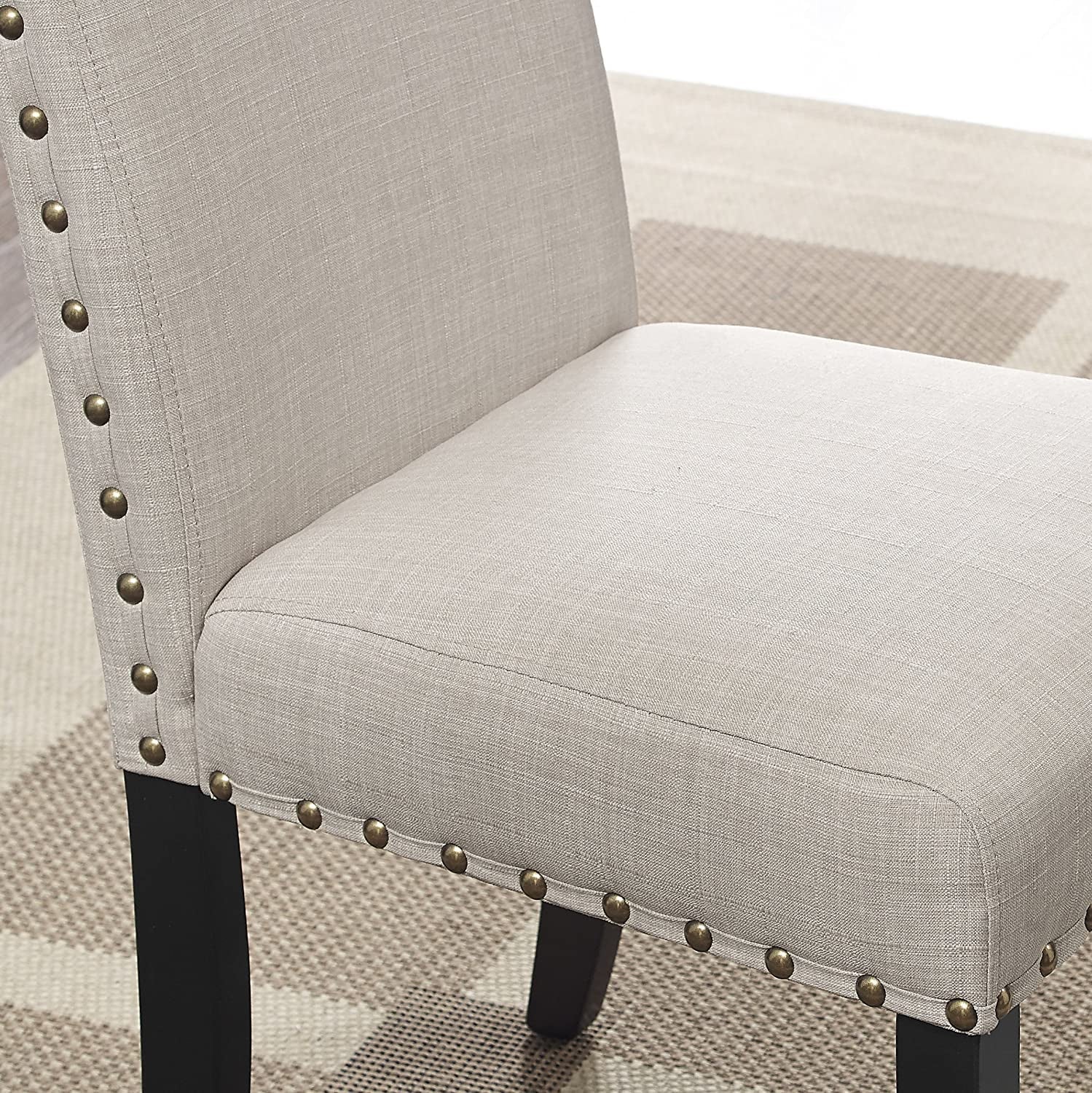 Gray upholstered chair with nailhead trim on a checkered floor