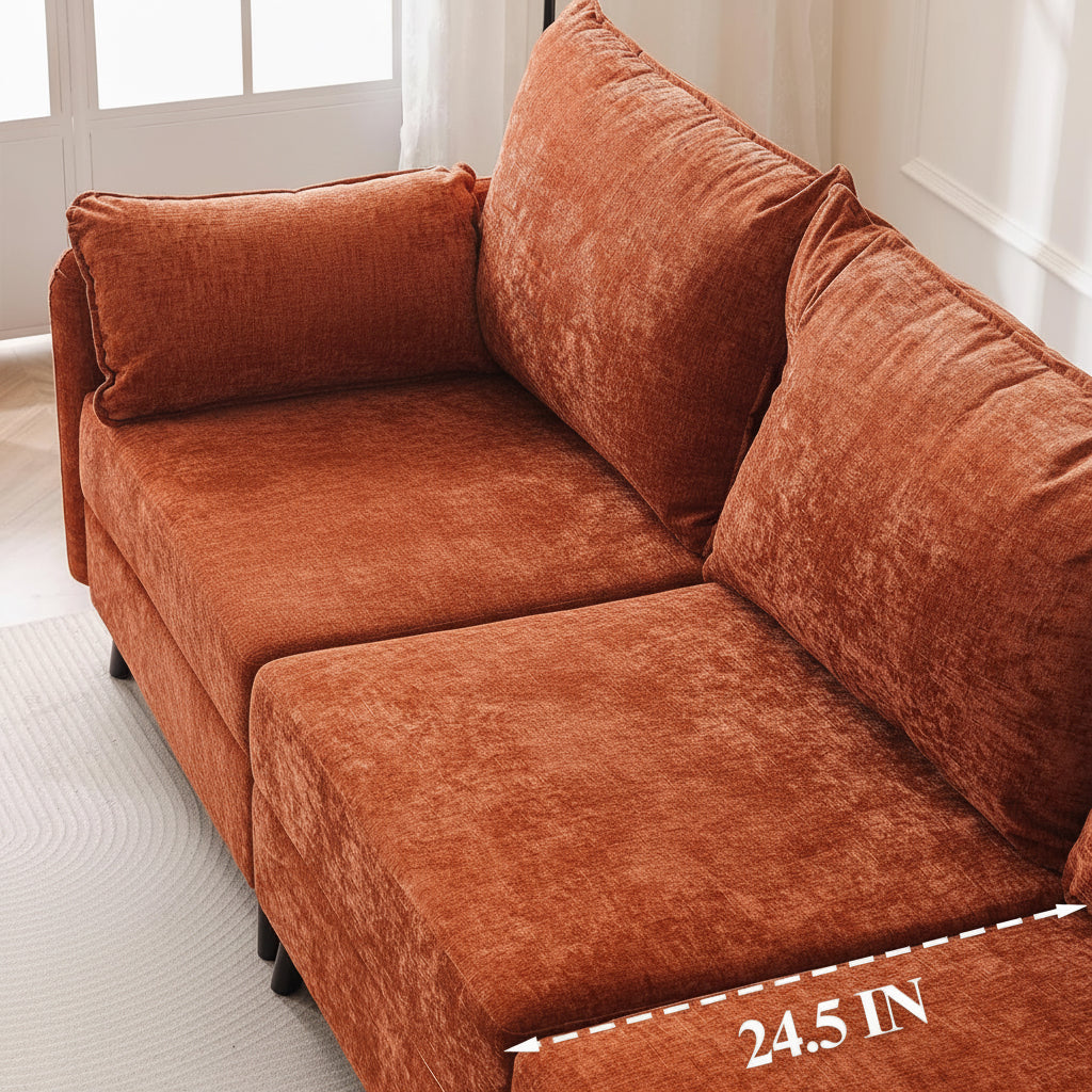 Woman reading a book on an orange couch with a white blanket, in a bright room.
