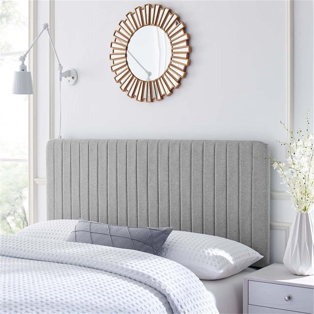 Gray upholstered headboard in a bedroom setting with a decorative mirror above it.
