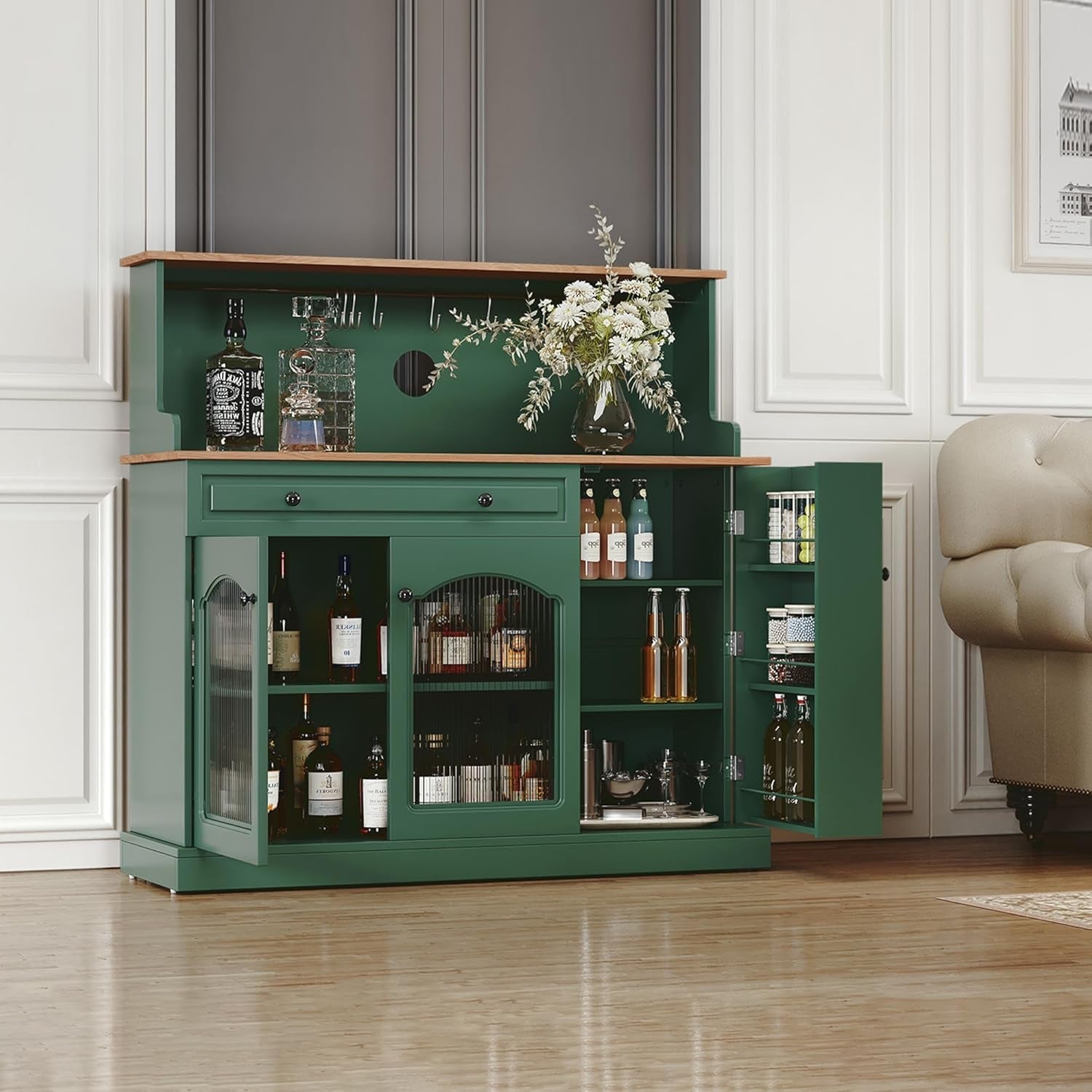 Green bar cabinet with open doors displaying bottles and decor in a room.
