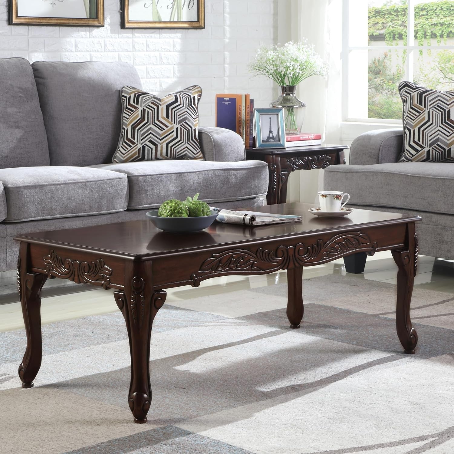 Wooden coffee table in a living room with gray sofas and decorative items.