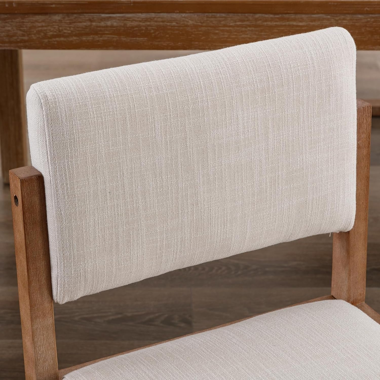  wooden chairs and white cushions in a bright room.