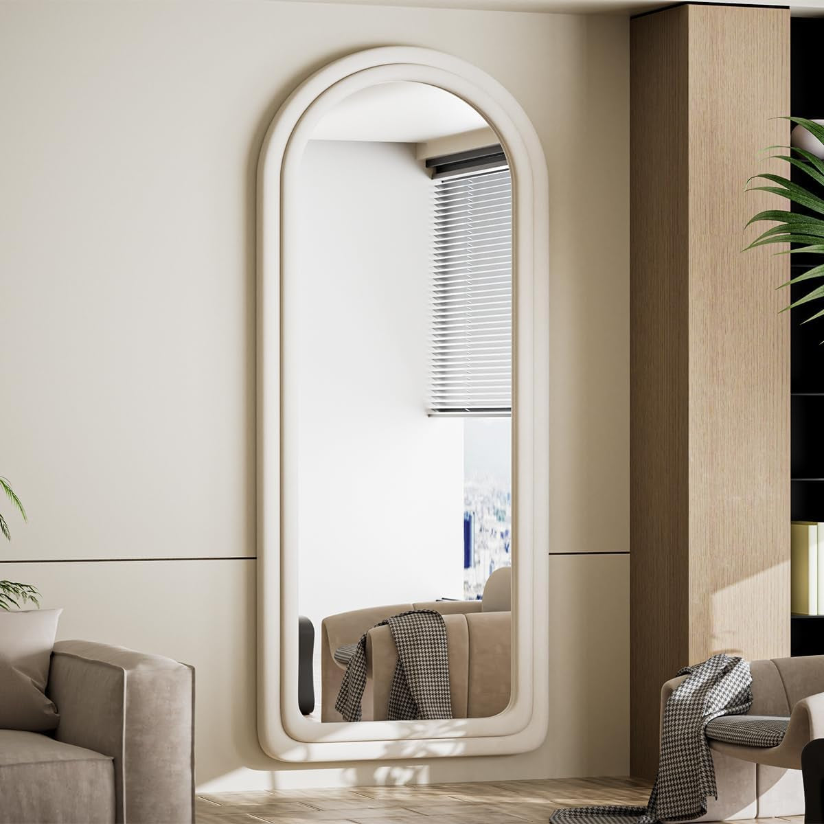 Large oval mirror on a wall in a modern interior setting with a sofa and plant.