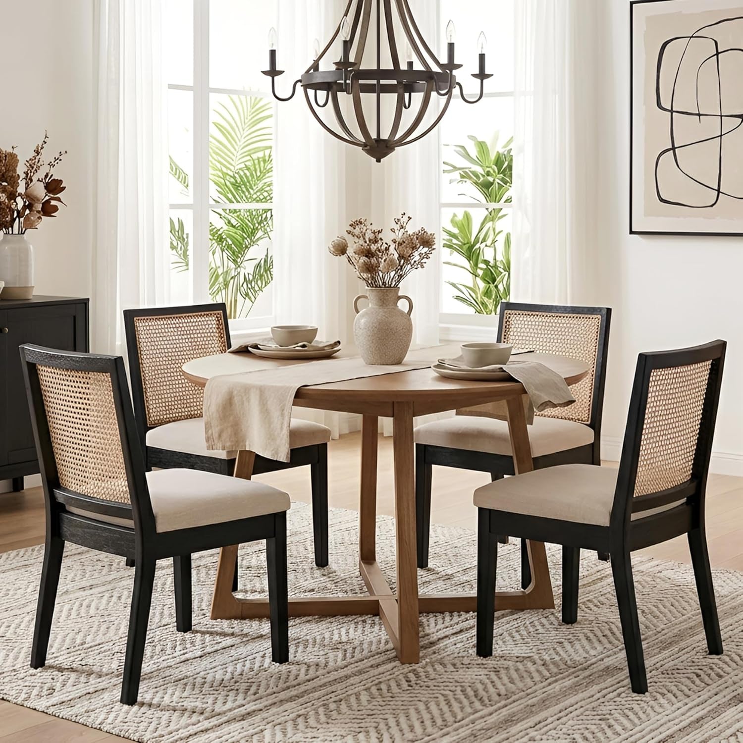 Dining room with a wooden table and black chairs with white cushions, featuring a chandelier and plants.