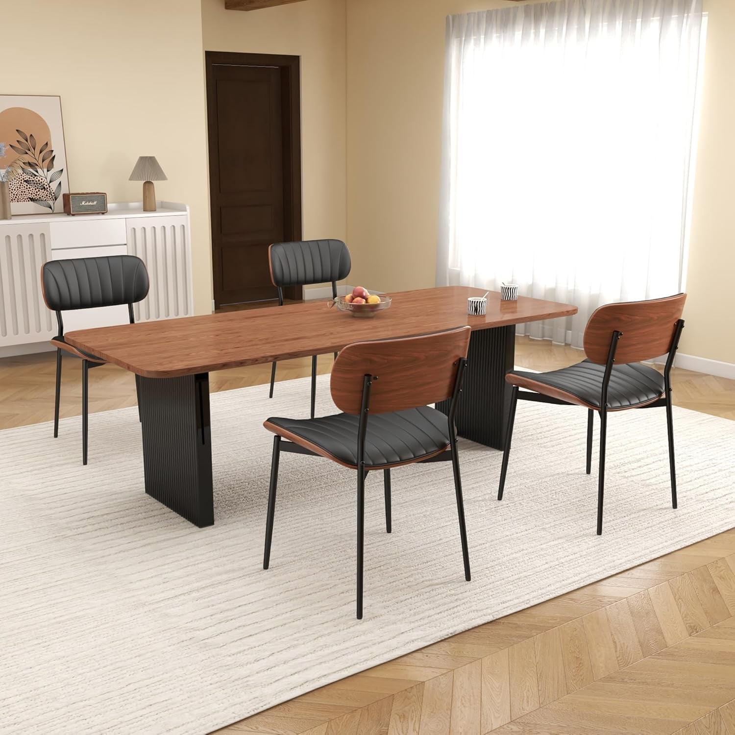 Two modern chairs with black seats and wooden backrests in a room with a table and decor.