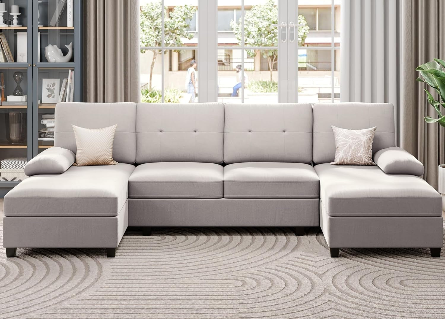 Gray sectional sofa in a living room with a bookshelf and window in the background.