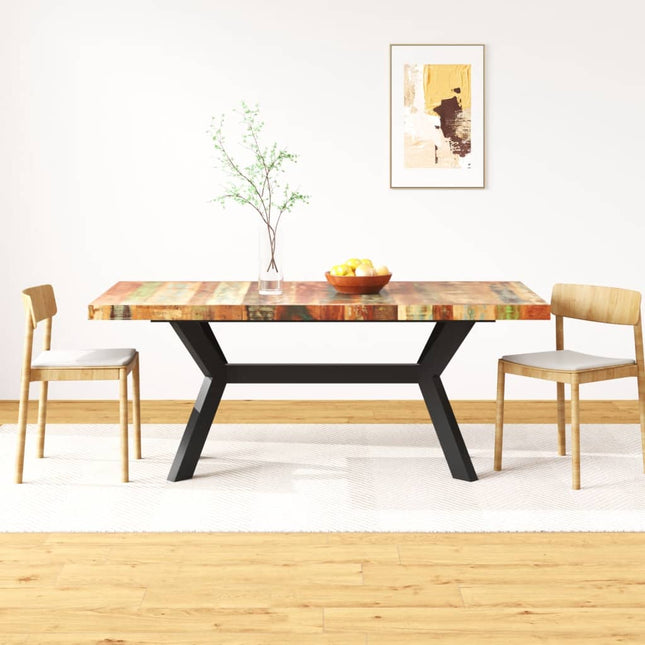 Dining table with colorful top and black legs in a room with two chairs.