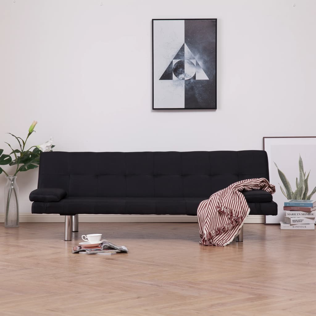 Black sofa bed in a room with a modern painting on the wall and decor items on the floor.