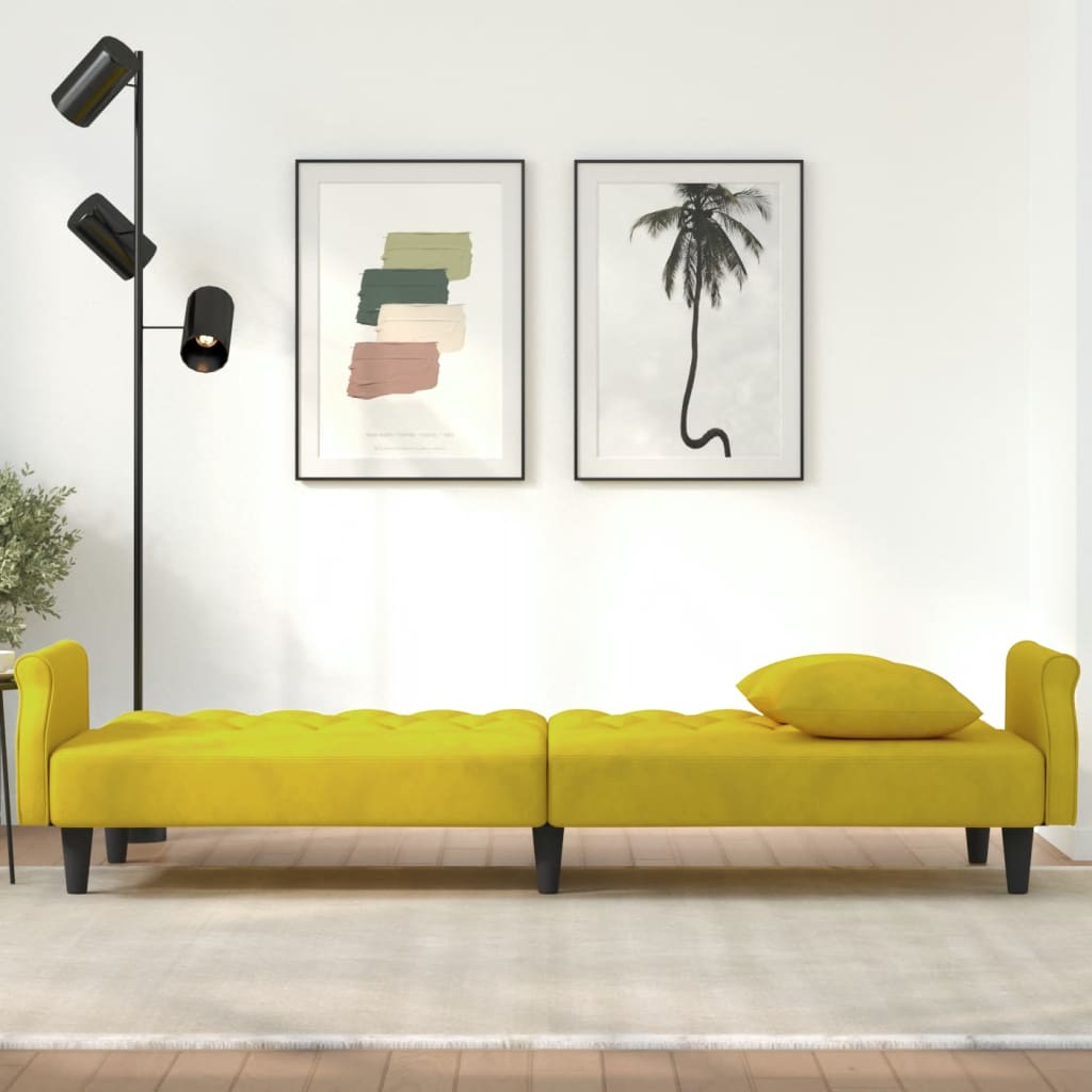 Yellow sofa bed in a room with wall art and a floor lamp.