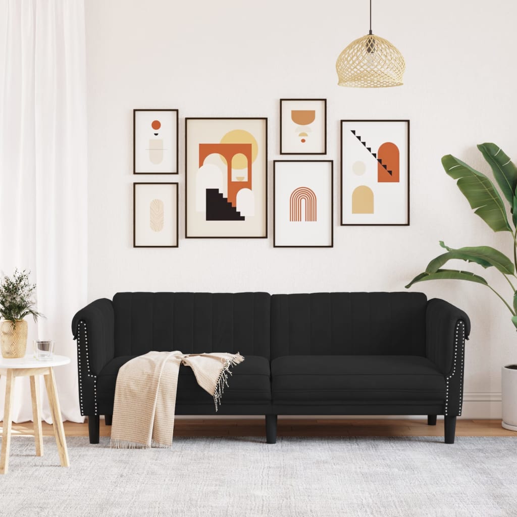 Black sofa in a living room with decorative wall art and plants.