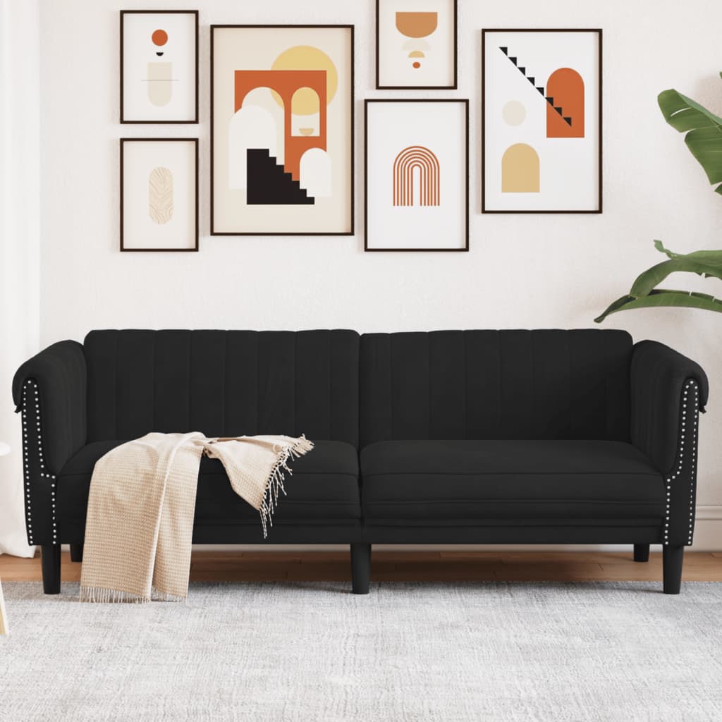 Black sofa with a beige blanket in a living room with abstract art on the wall.