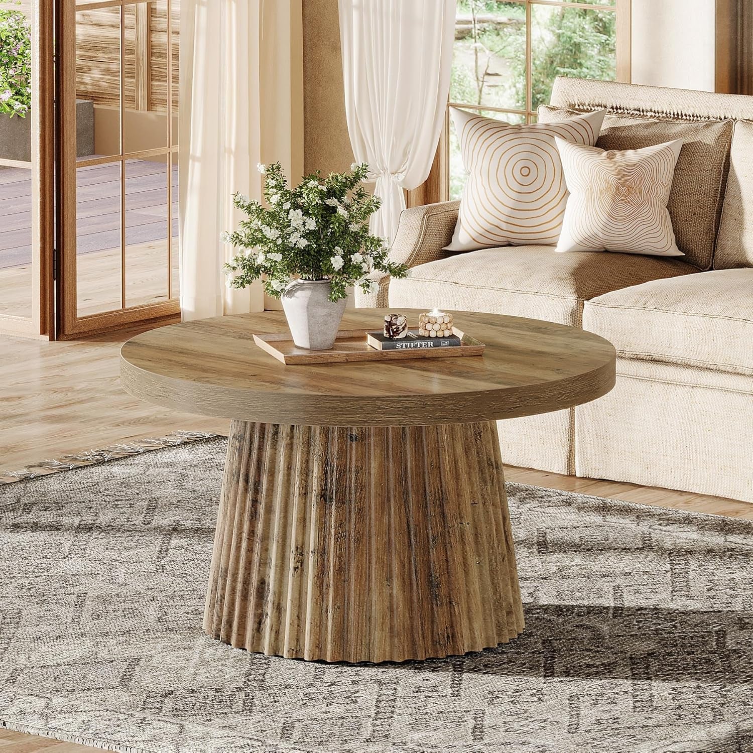 Round wooden coffee table in a living room with a sofa and decorative items.