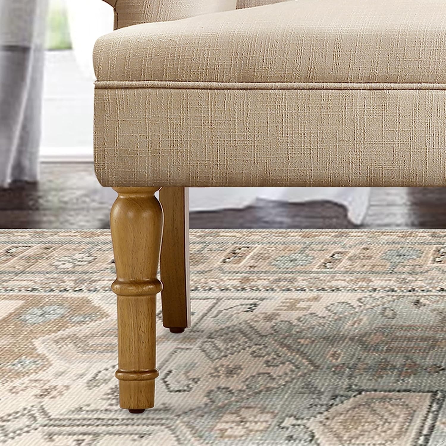 Close-up of a beige upholstered chair with wooden legs on a patterned rug.