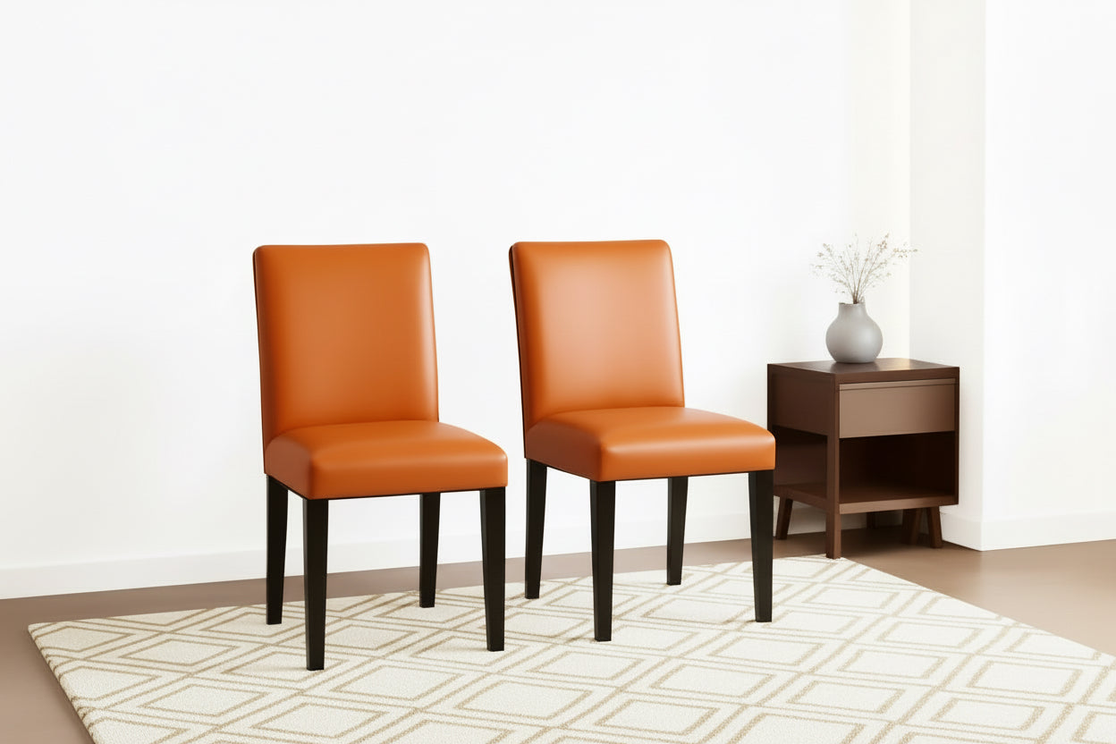 Two orange chairs with black legs in a room with a beige wall and small table.