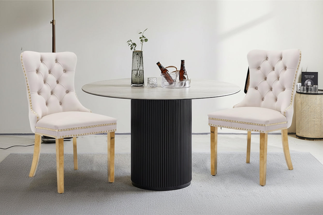 Dining chairs with tufted button design and studded trim, featuring a round table.