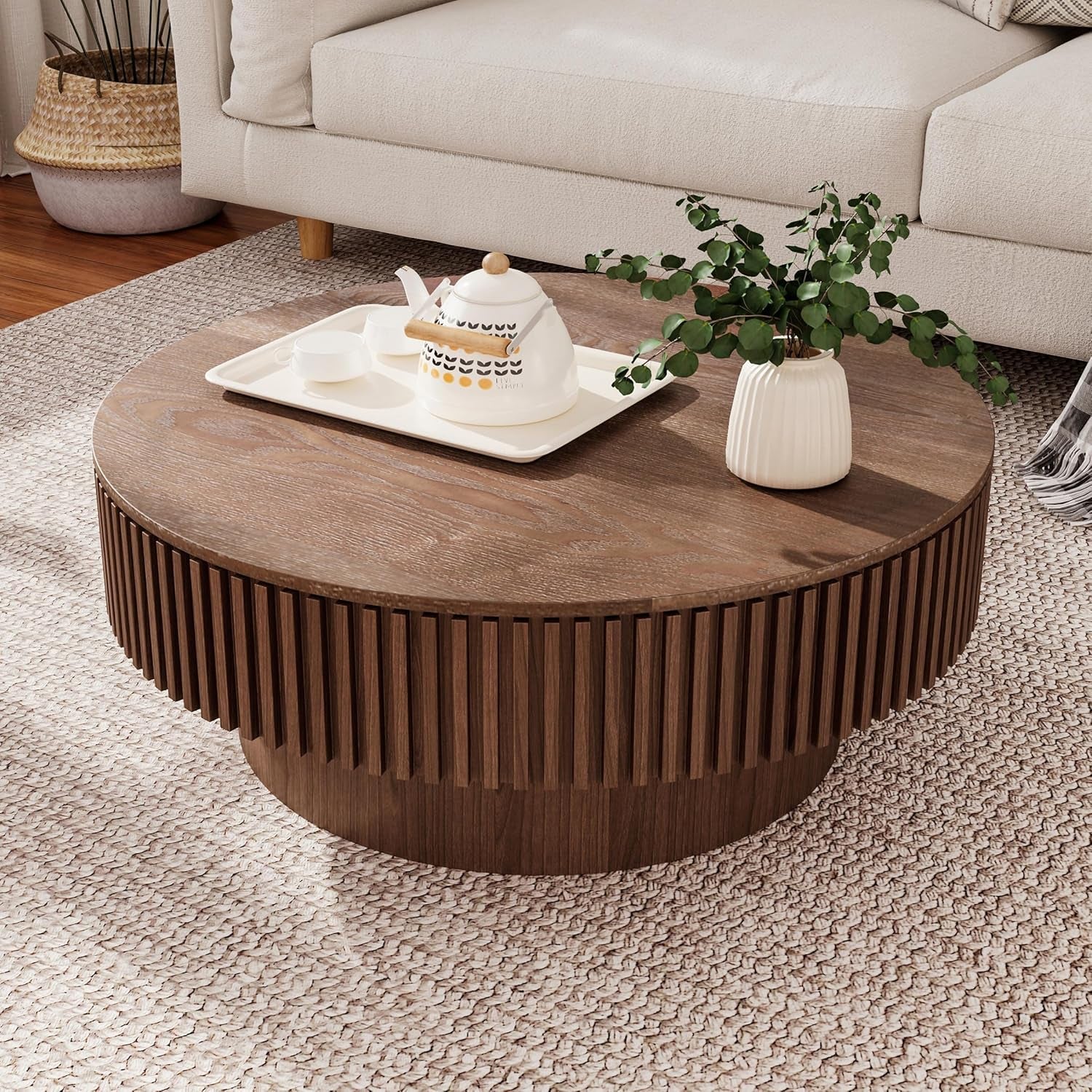 Round wooden coffee table with decorative items in a living room setting
