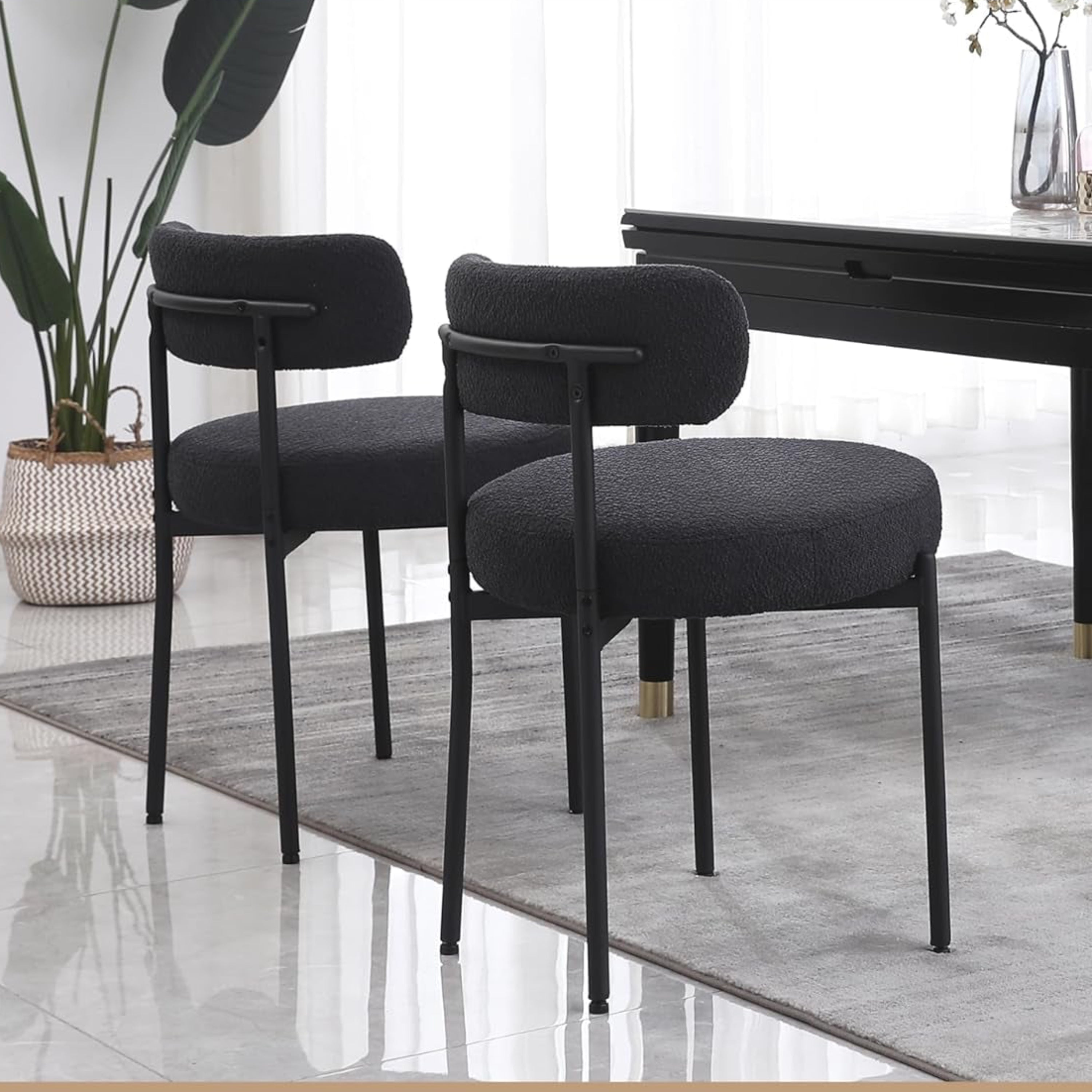 Modern dining room with black chairs and a table, featuring metal leg support.
