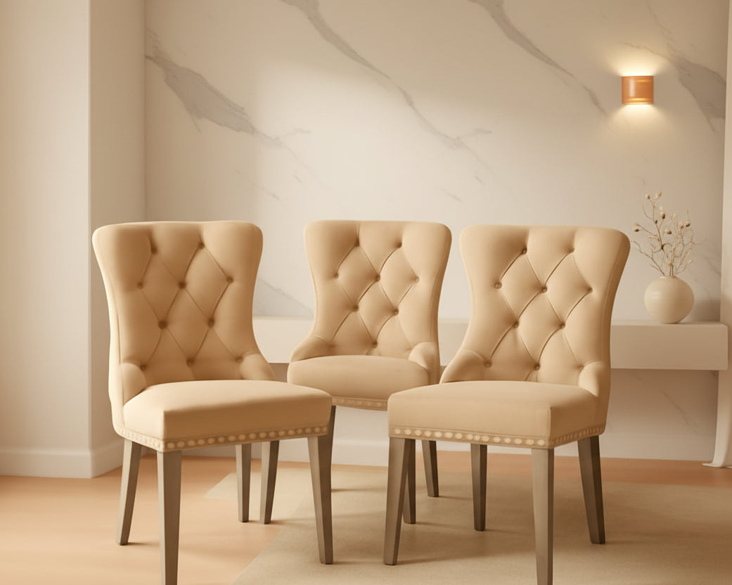 Three beige upholstered chairs in a room with warm lighting.