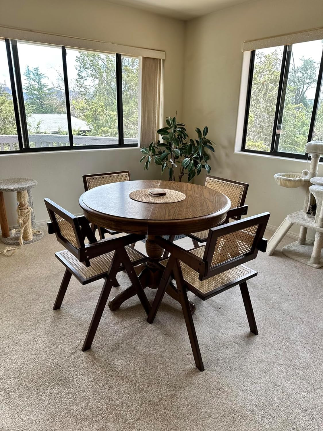 Dining area with wooden table and chairs in a room with large windows.