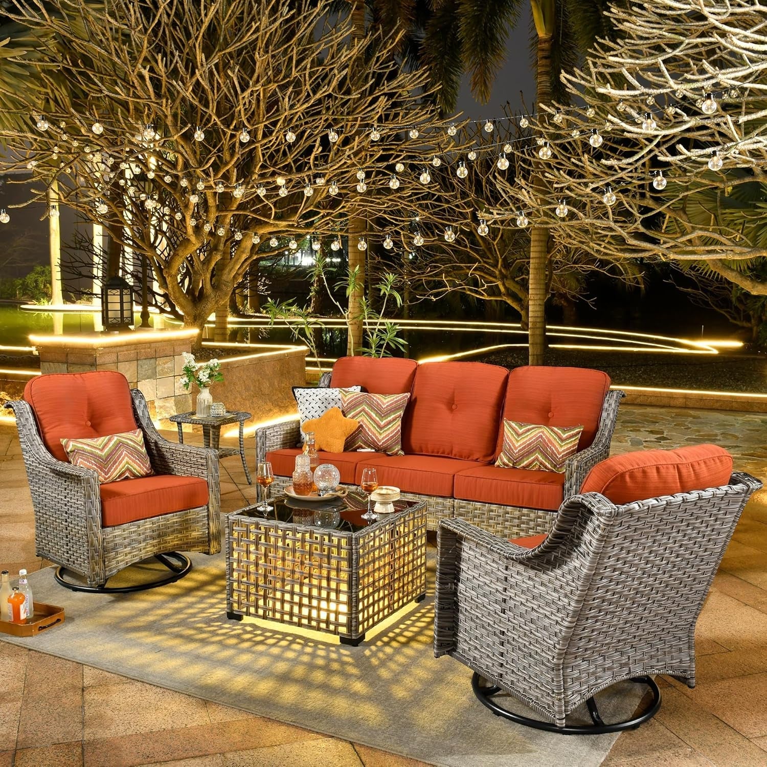 Outdoor patio set with red cushions and a fire pit table on a patio at night.