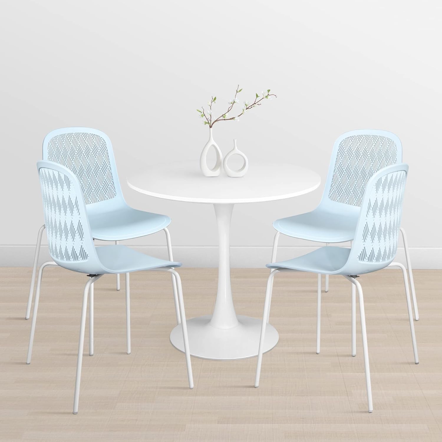 Round white table with four light blue chairs on a wooden floor.