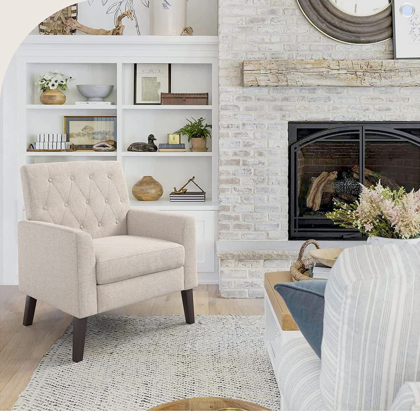 Beige armchair in a living room with a fireplace and decorative shelves.