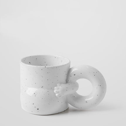 White ceramic mug with speckled pattern on a light gray background