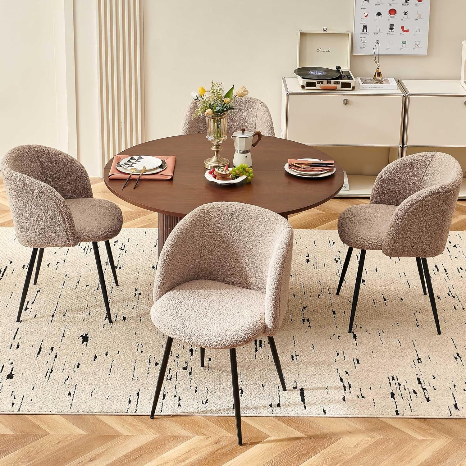 Dining room with a round wooden table and four chairs on a patterned rug.