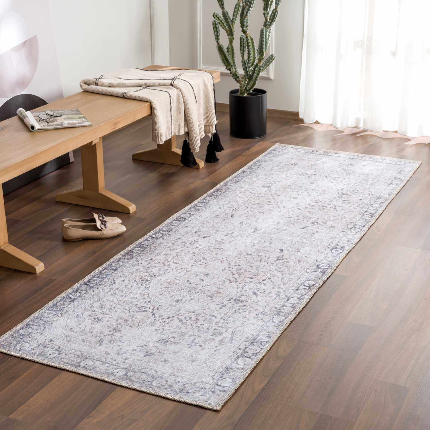 Long rectangular rug on a wooden floor with a bench and plant in the background