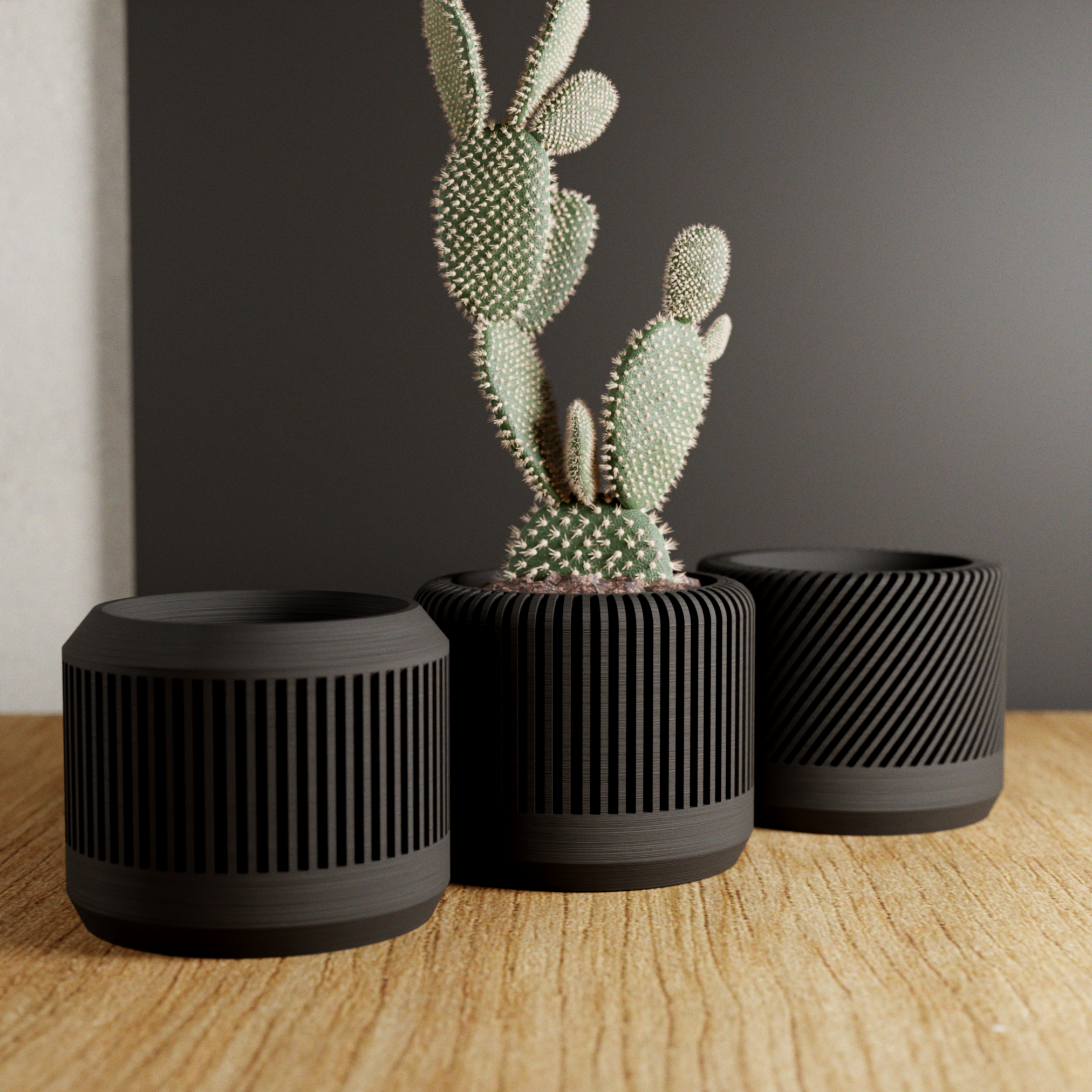 Three black textured planters with a cactus on a wooden surface against a dark wall.