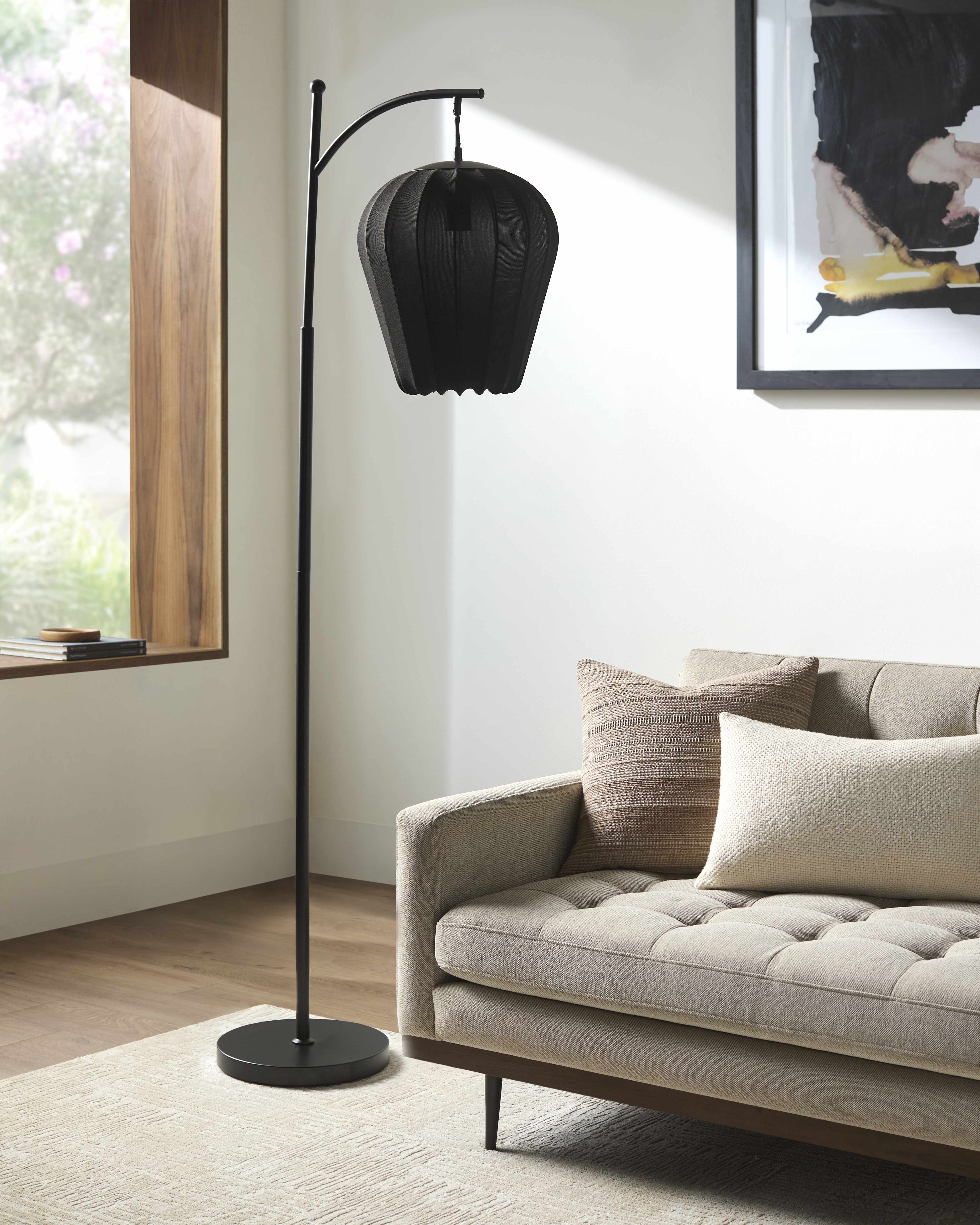 Black floor lamp in a living room with a sofa and window