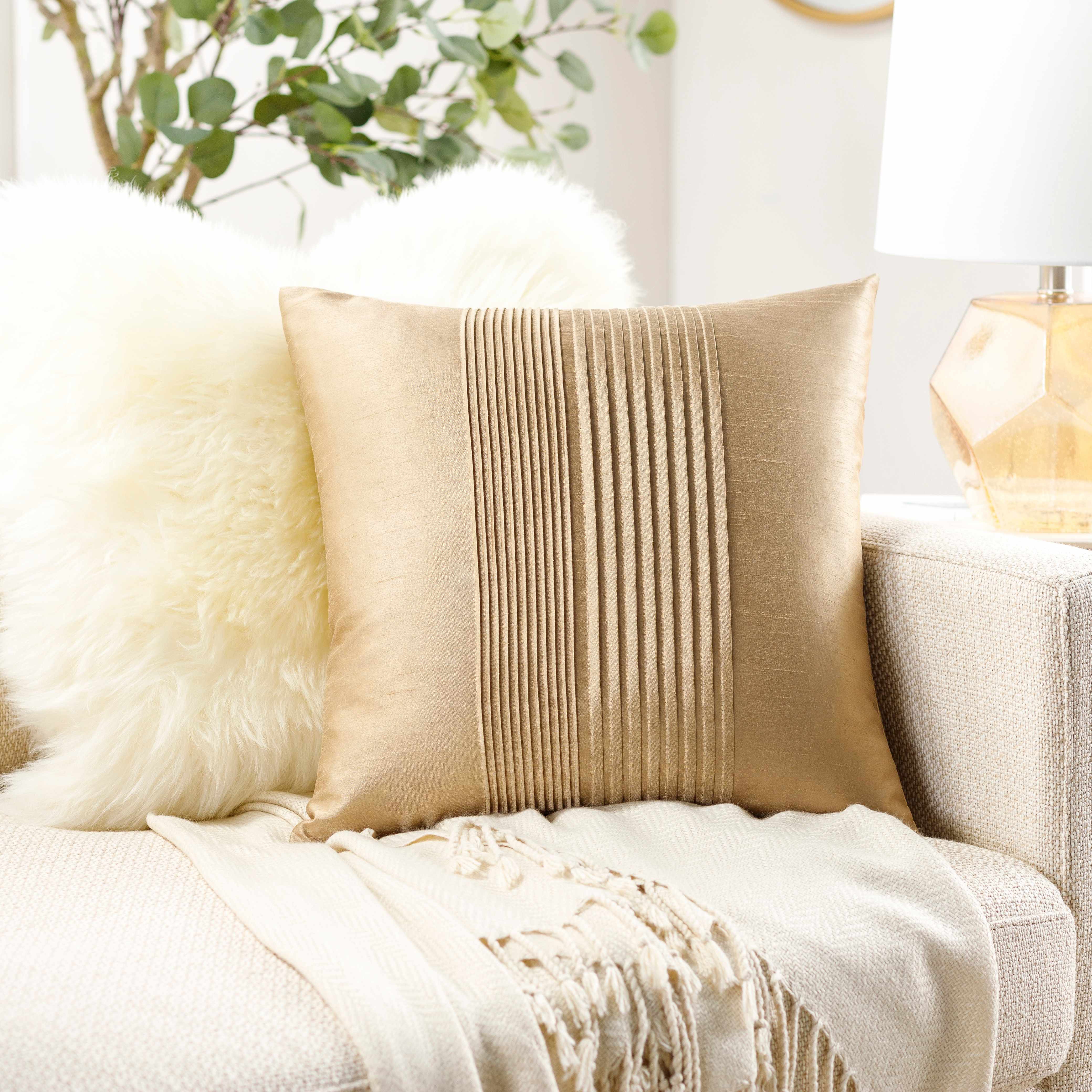 Beige pillow on a white sofa with decorative elements in a cozy living room setting.