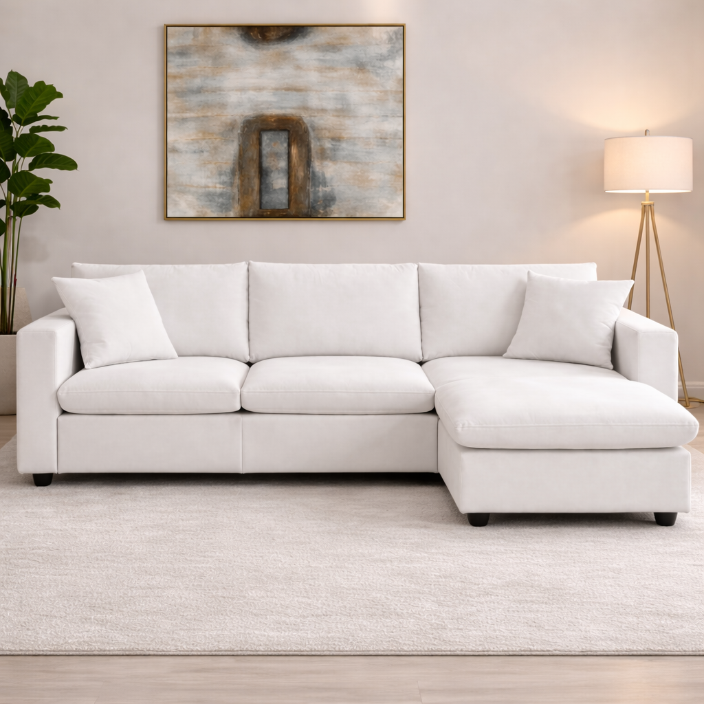 White sectional sofa in a living room with abstract art and a lamp.