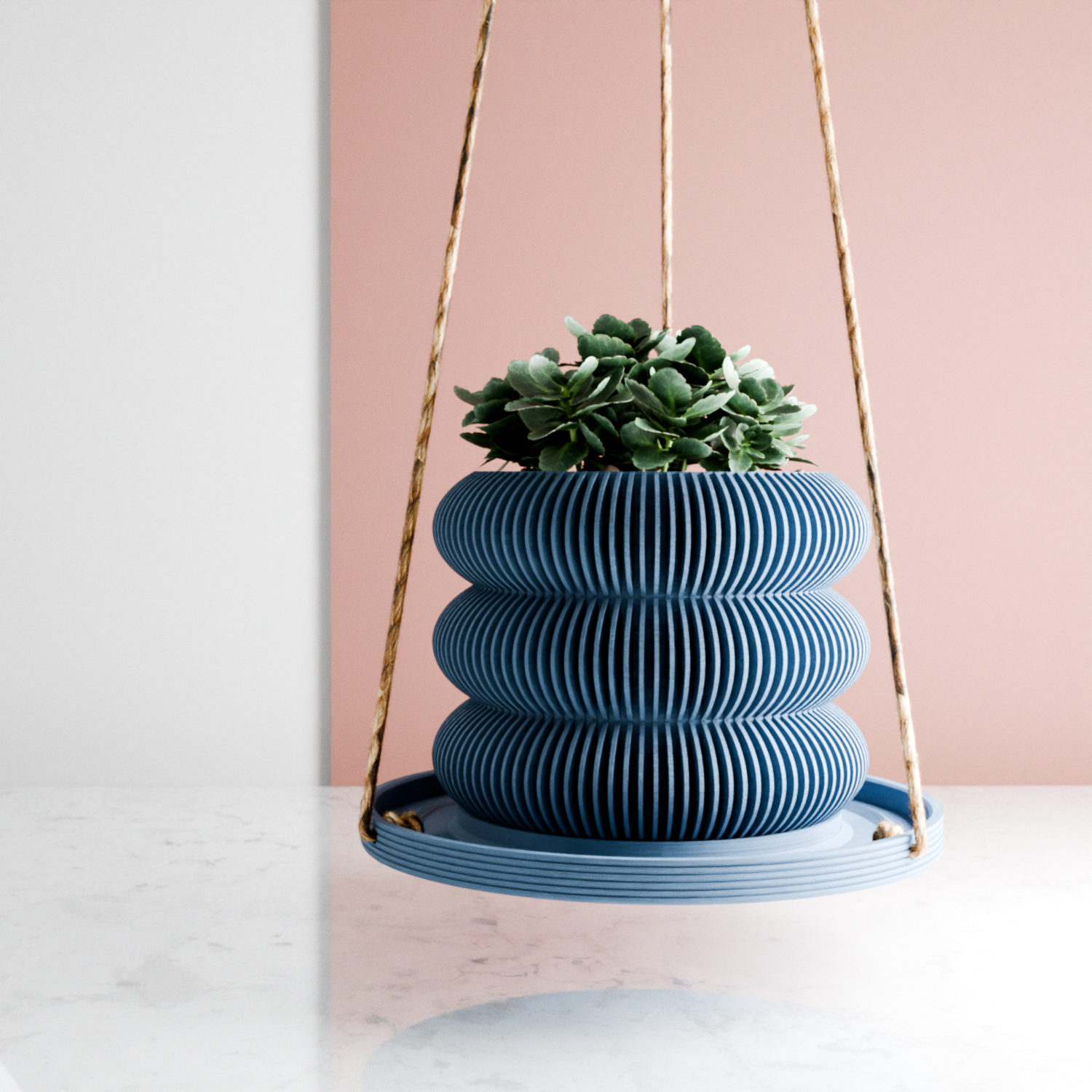 Blue hanging planter with succulents against a pink wall