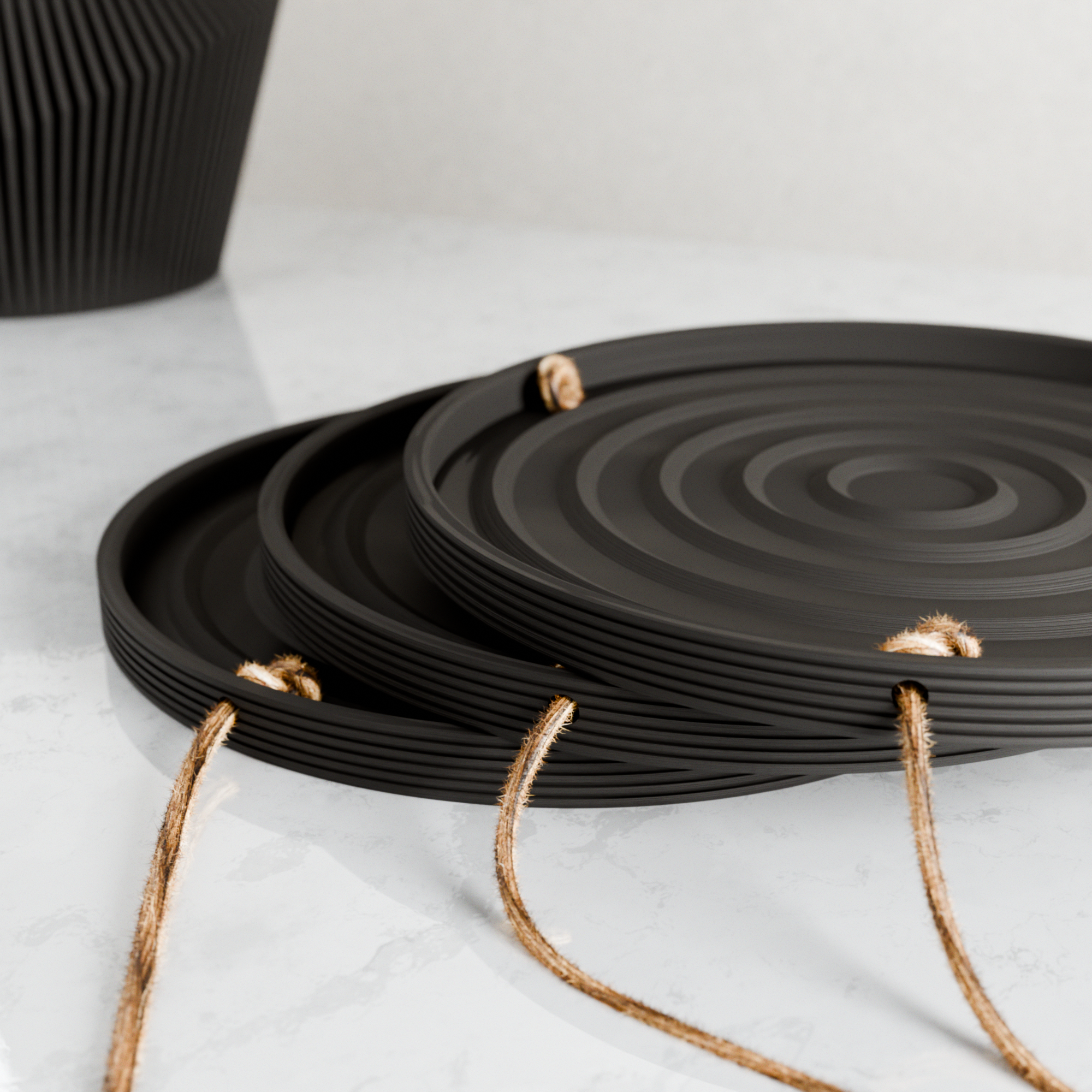 Set of black ceramic trays with woven handles on a light background