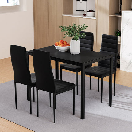 Black dining table with four chairs in a room setting.