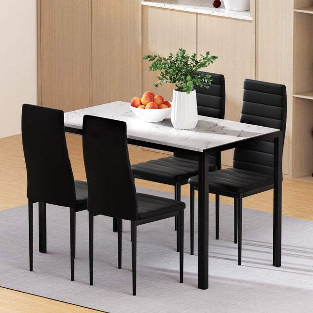 Dining table set with black chairs and a bowl of fruit in a room.