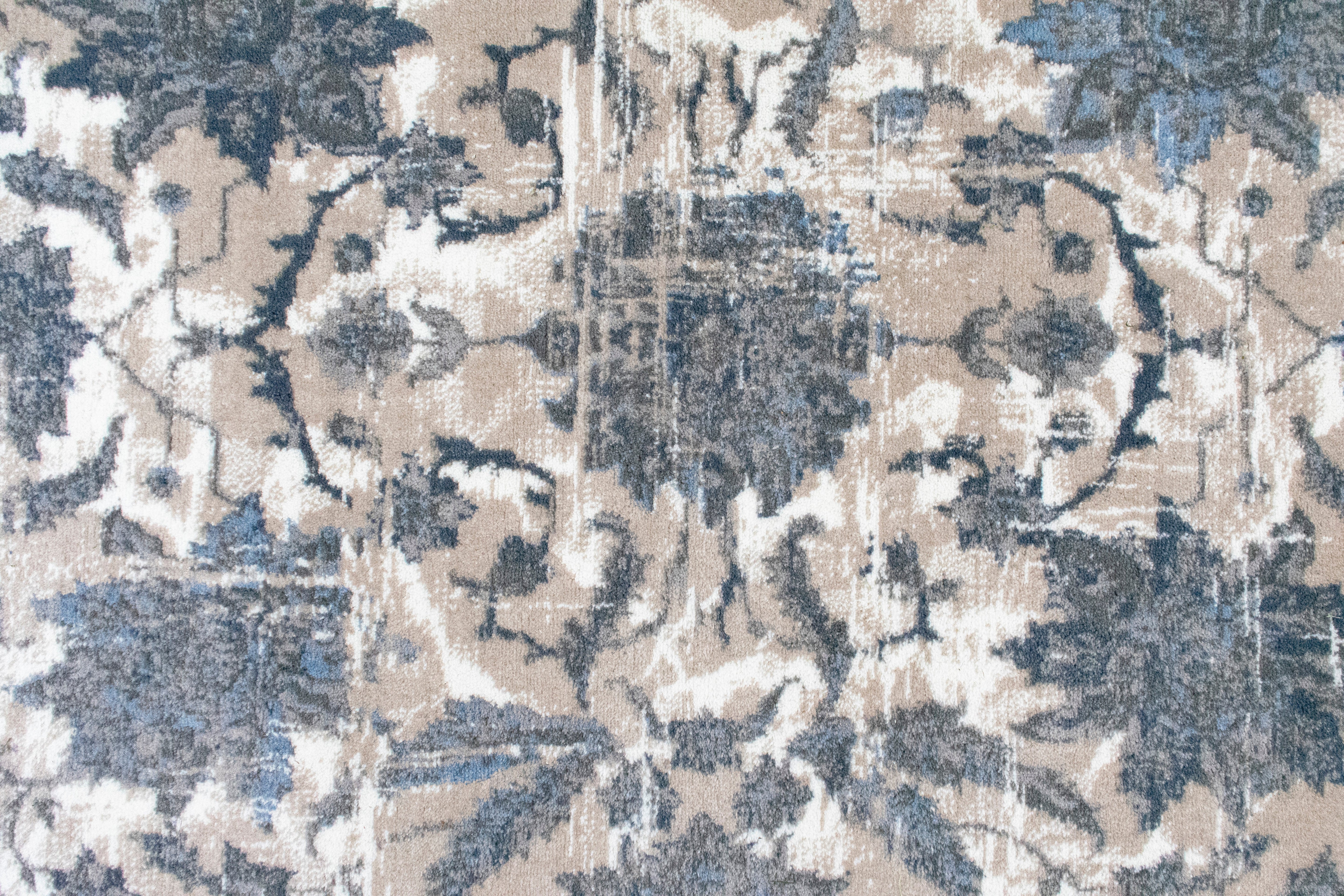 Close-up of a textured fabric with floral pattern in beige, blue, and white.